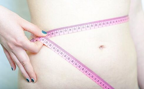 Dievča si meria pás, aby zaznamenalo výsledky dodržiavania Dukanovej diéty